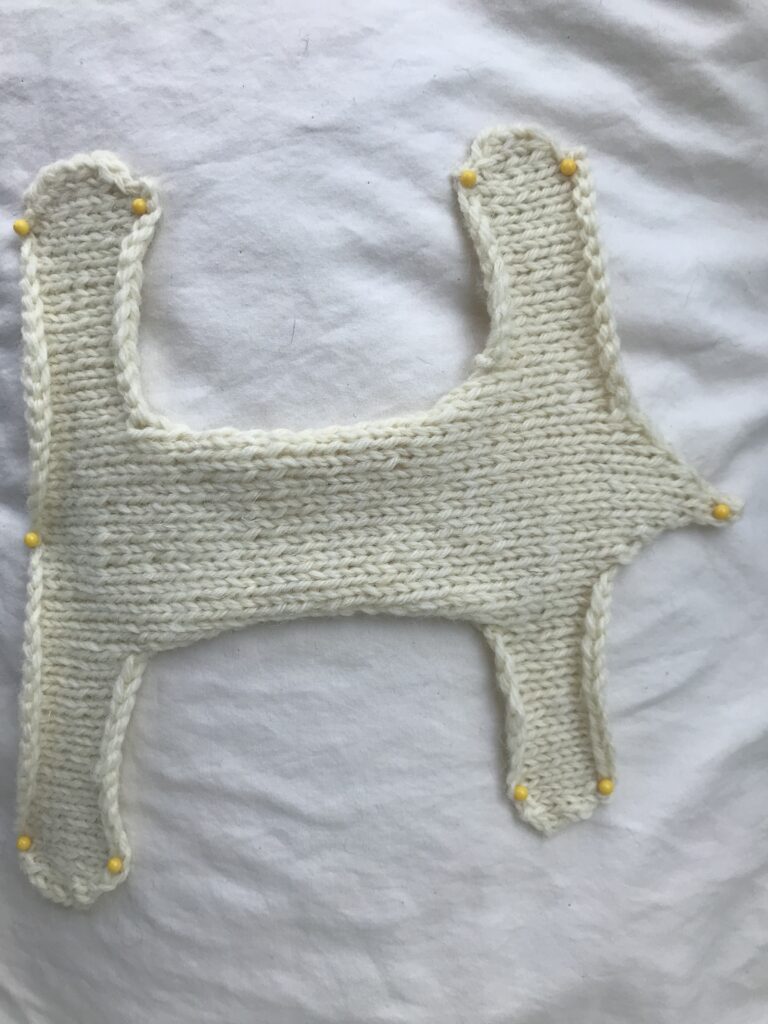 white front of knit rabbit body held down by yellow pins on a white background Rabbit Knitting Pattern FREE