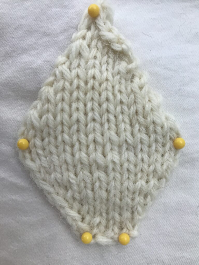 knit diamond shape with white yarn on white background with yellow pins Rabbit Knitting Pattern FREE