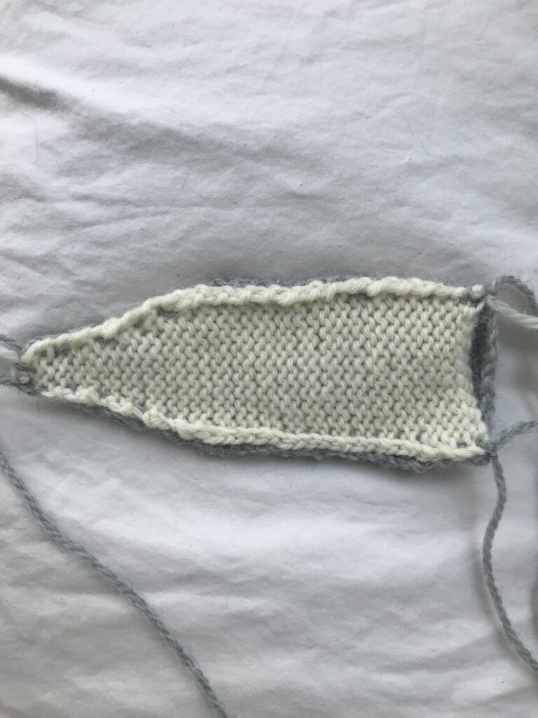 unfinished white knitted ear turned inside out on white background