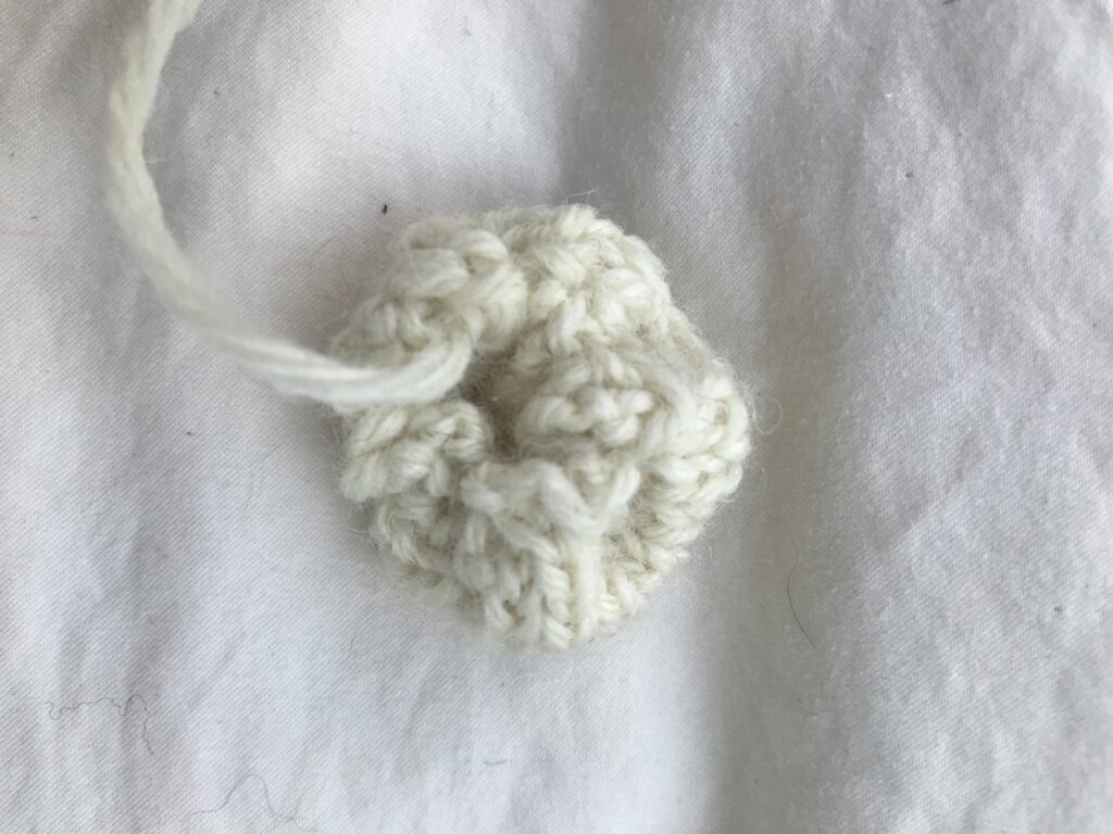 the underside of a white knitted round tail on a white background