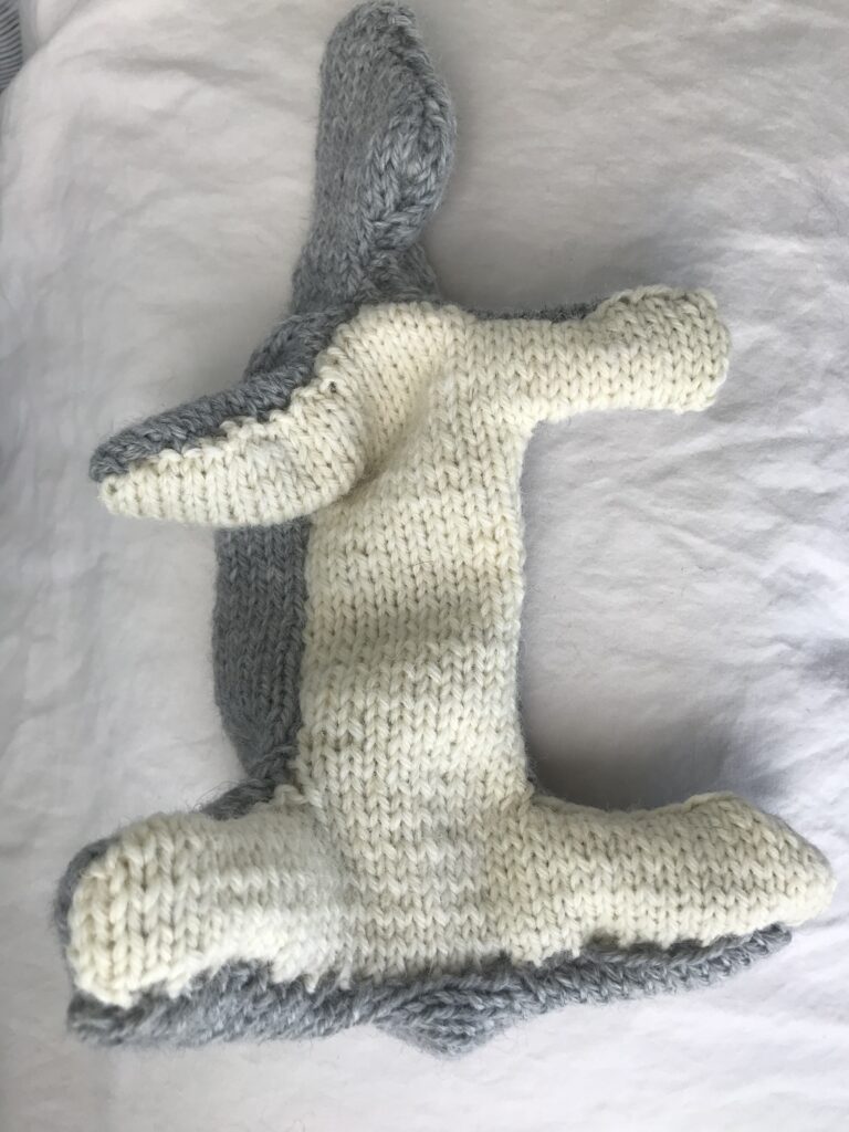 unfinished knitted rabbit body turned right side out on a white background