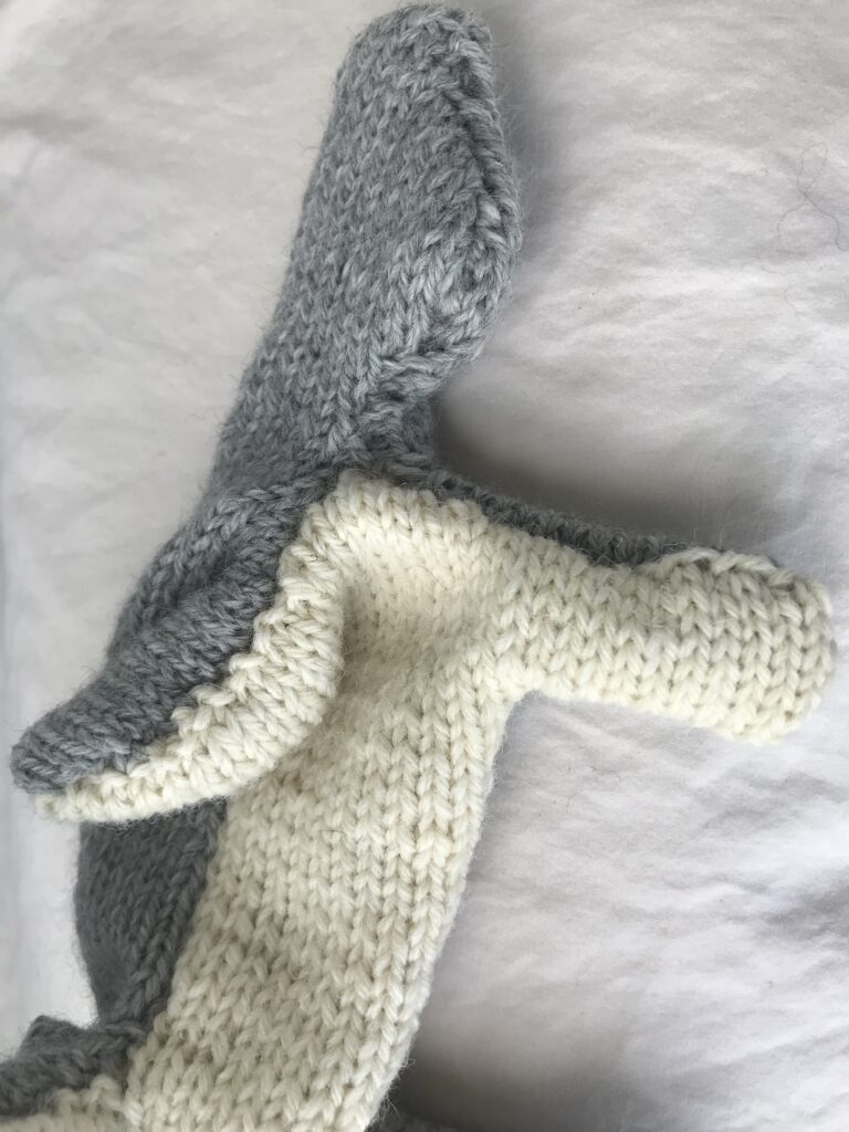 grey and white knitted rabbit turned right side out on a white background