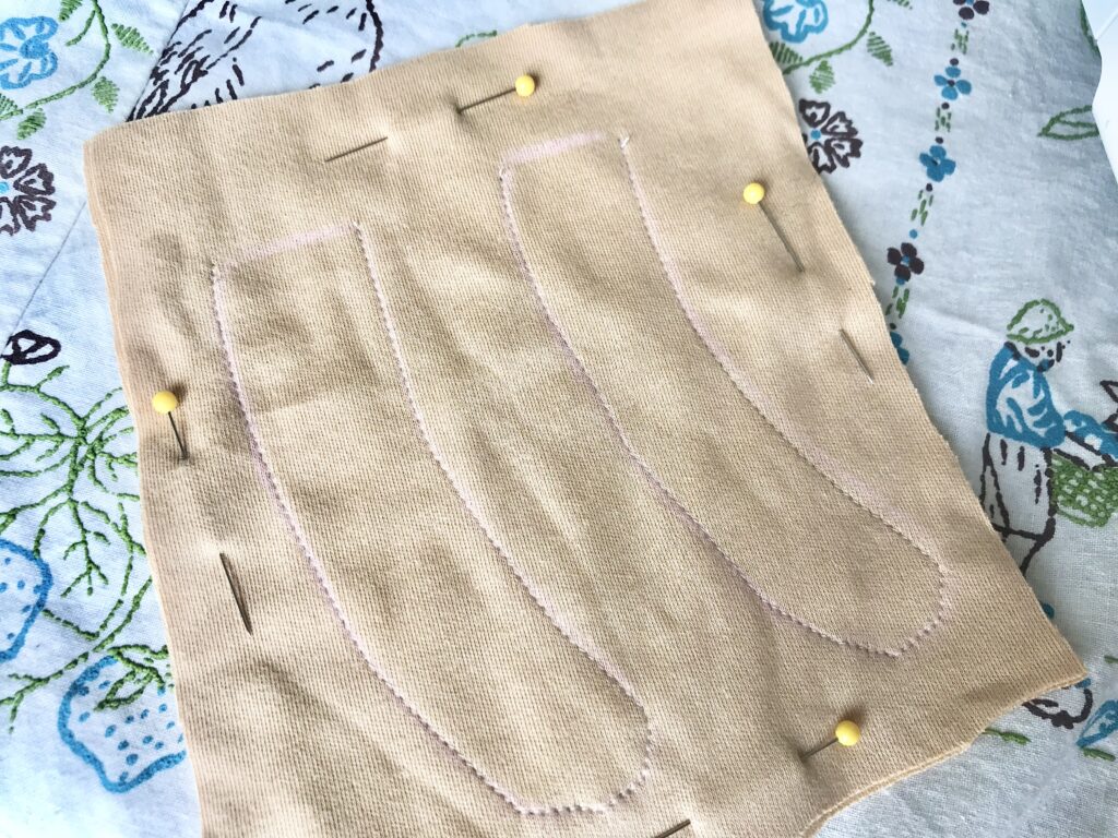 stitched tan fabric with yellow pins on a tablecloth
