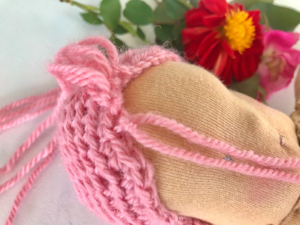 waldorf doll weft being made with red flower in background