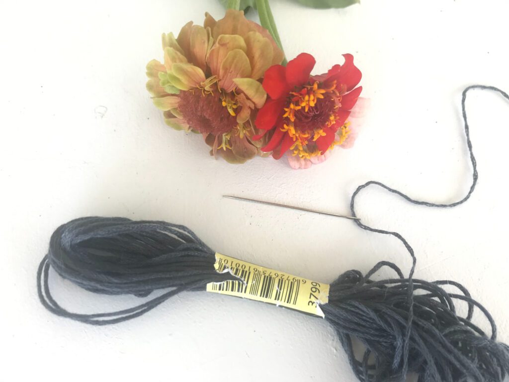 3799 grey embroidery thread on a needle with zinnias on a white background