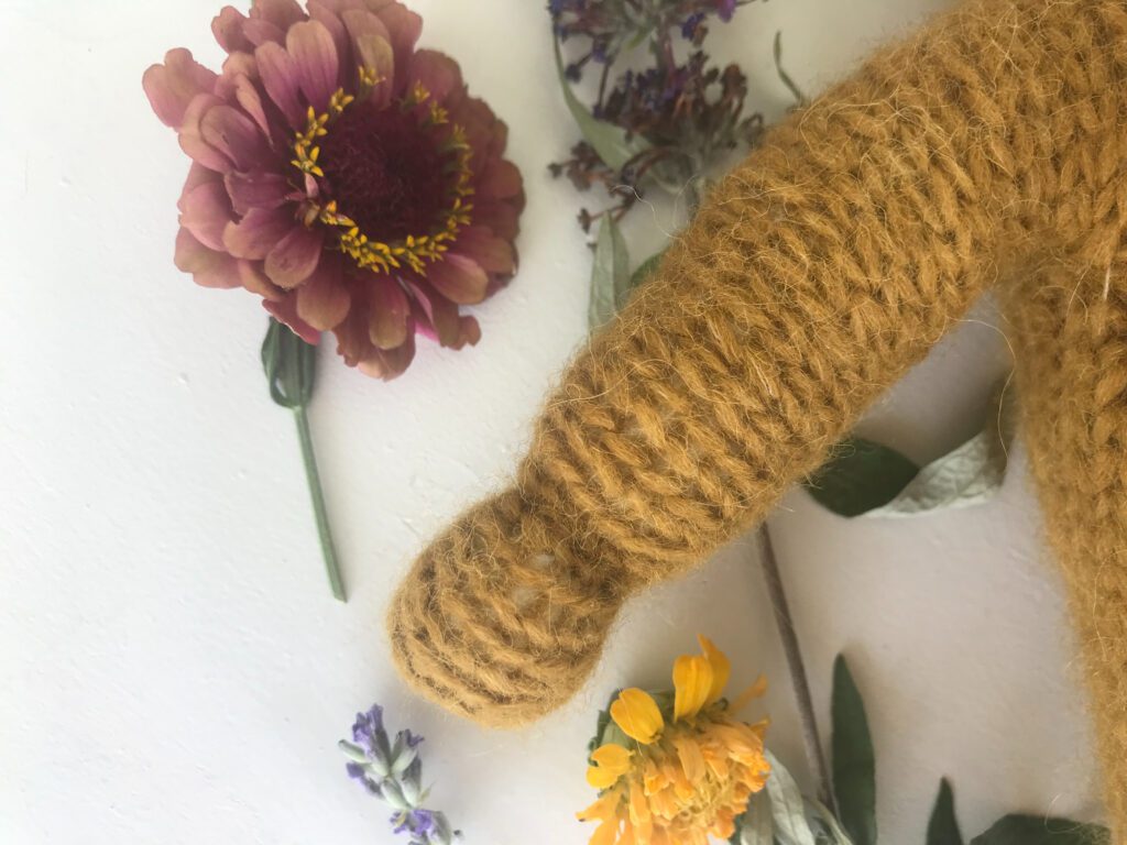 arm and hand on a knitted waldorf doll with flowers