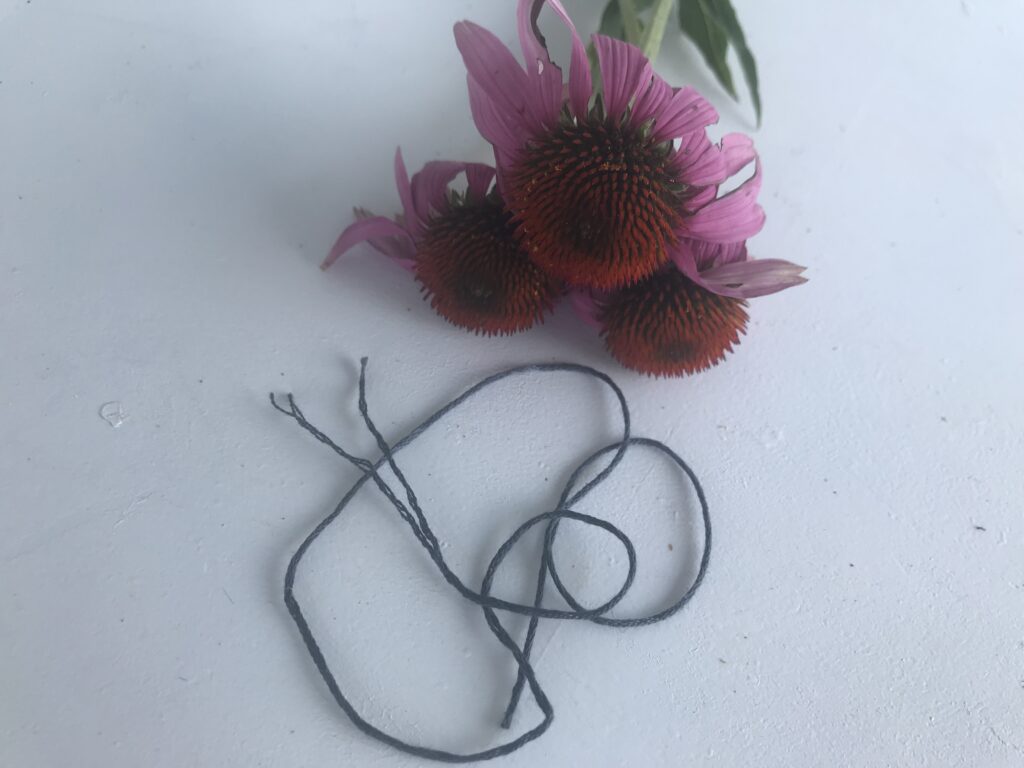 grey embroidery thread split in half with flowers in background