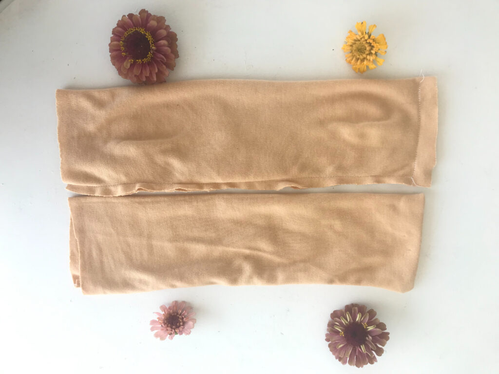 two tan rectangular pieces of fabric sewn to make waldorf doll head with zinnias 