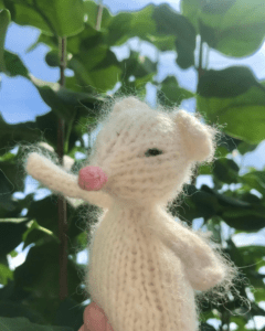 knitted white mouse with leaves and sky in background