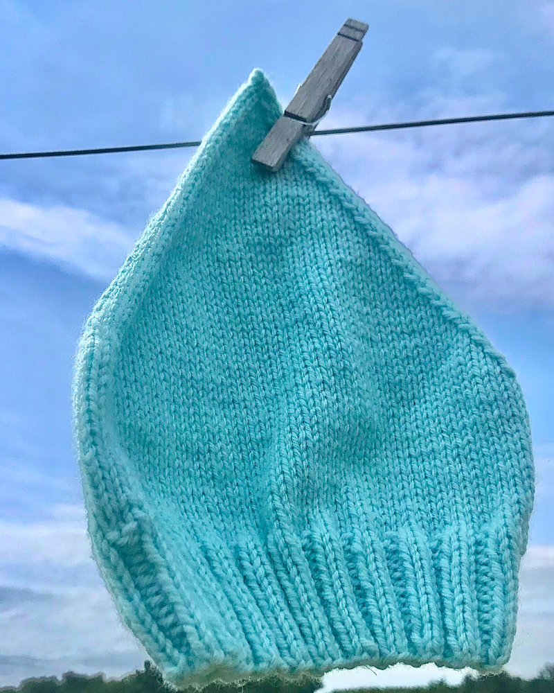 blue baby hat hanging on a clothesline