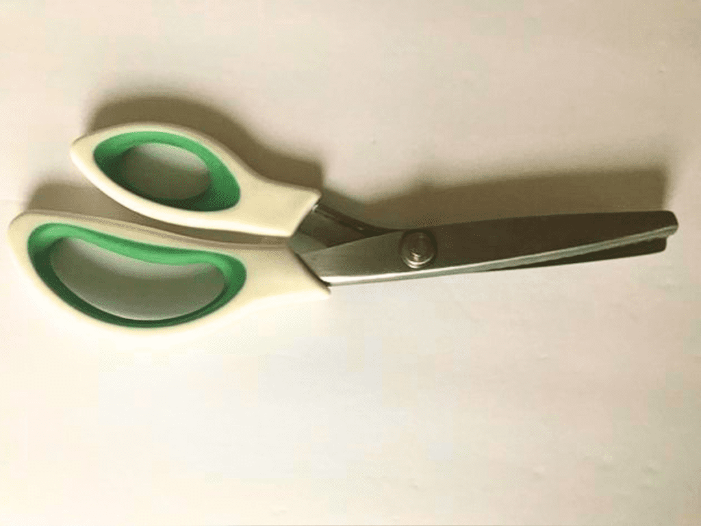 green and white pinking shears on white background