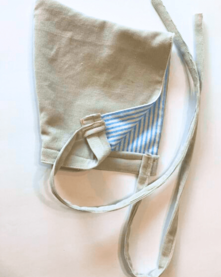 grey newborn hat with blue pinstripes and ties on a white background